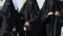 Saudi women cross a street