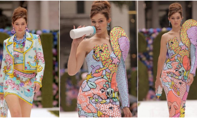 Gigi Hadid hits the Moschino runway in two different looks while feeding on a bottle