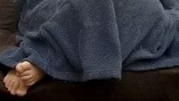 A wanted guy is discovered hiding under a blanket with his feet protruding