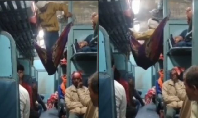 A man creates his own bed with a blanket in the train aisle