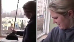 Ukrainian woman tearfully sings the national anthem while cleaning the glass of her bombed home