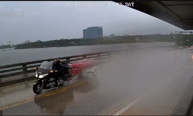 Watch: Terrifying moment motorcyclist hauling a trailer dangles off the gap of a Florida drawbridge