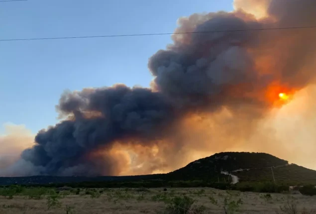 Texas lakeside houses burn in a wildfire in intense heat