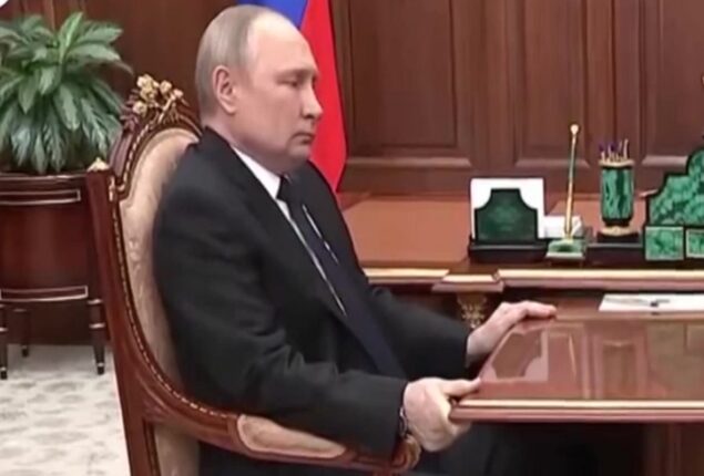 At a war meeting, grimacing Putin grabs the table once more
