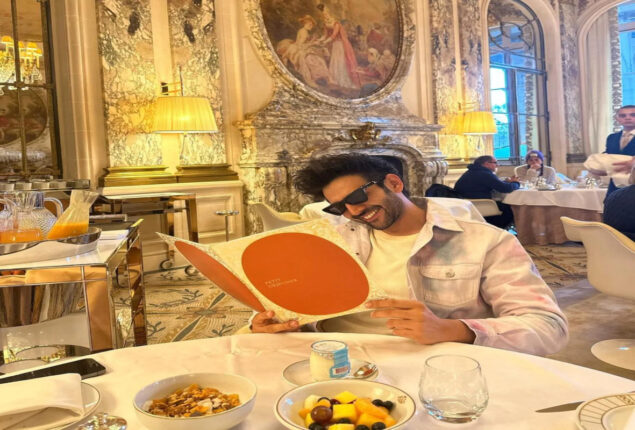 Kartik Aaryan poses smiling while reading menu at Paris hotel